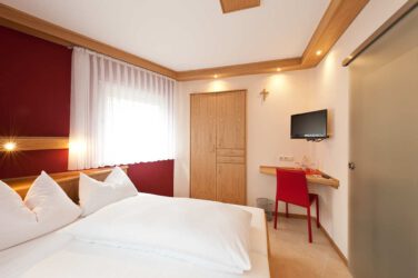 Gästezimmer mit Einbauschrank aus Wildeiche und Ganzglasschiebetür zur Nasszelle